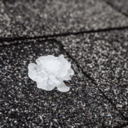 An illustration depicting the impact of hail on roofs, showing various roofing materials affected by hail damage.