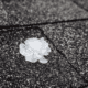 An illustration depicting the impact of hail on roofs, showing various roofing materials affected by hail damage.