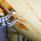A person assessing their current attic insulation.