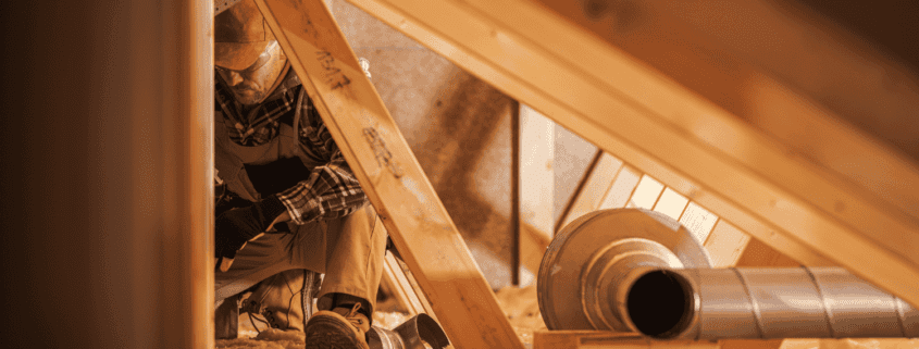 A person inspecting an attic for insulation and ventilation issues.
