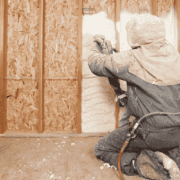 Filling stud bays with loose fill insulation by hand.