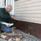 Inspecting the exterior of a home for foundation issues.