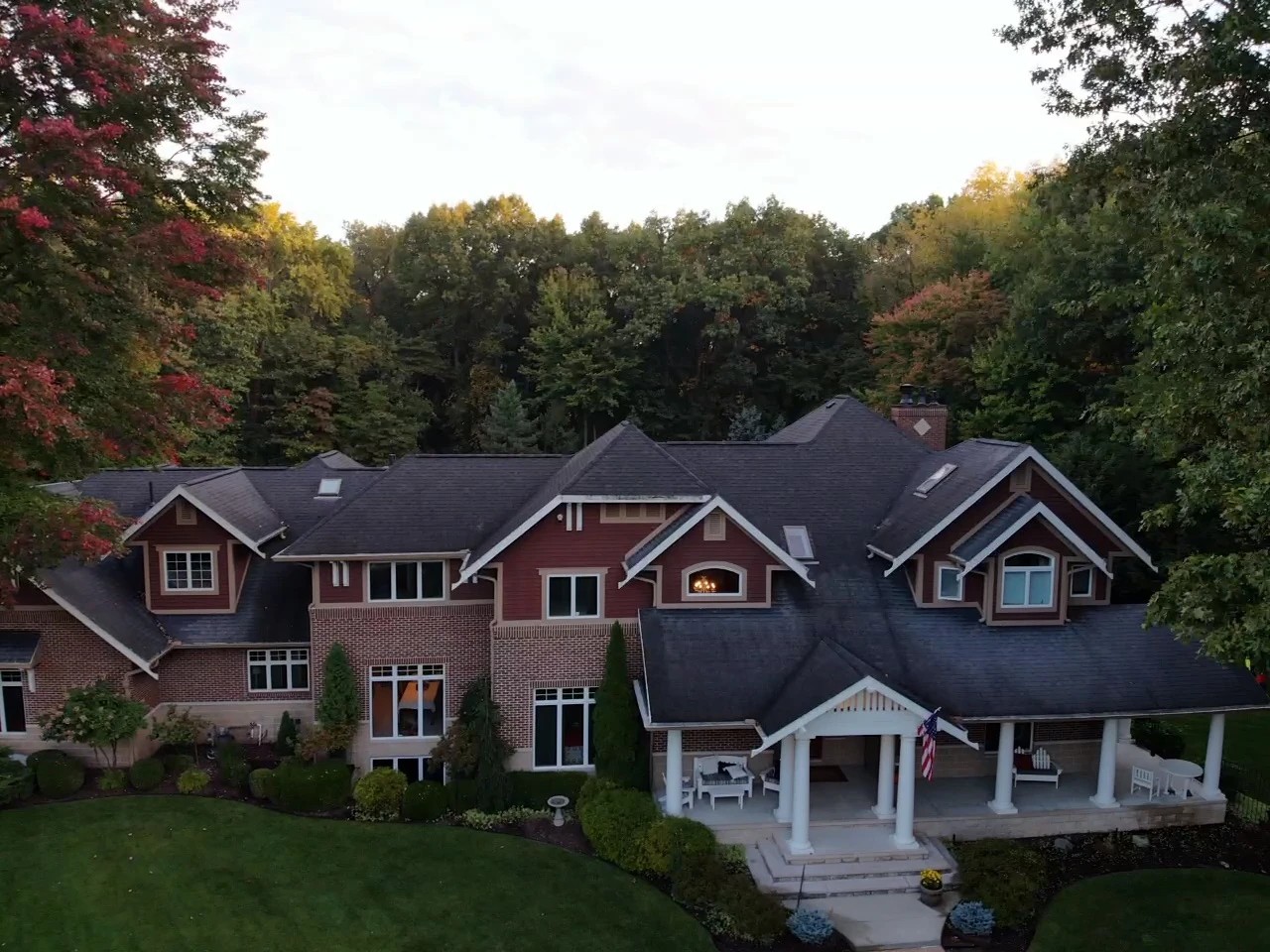 Lakeville, IN 3 An aerial view showcases a magnificent multi-gabled brick home with a sprawling dark roof and a columned front porch, illustrating a property perfected by professional exterior services.