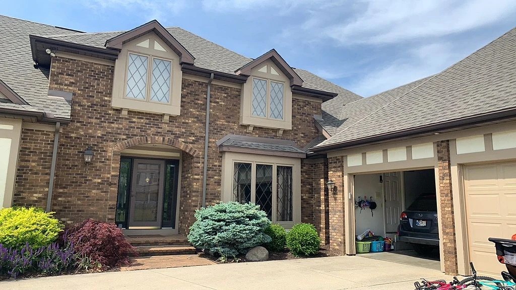 New Carlisle, IN 3 A striking brick home featuring distinctive diamond-pane windows, a multi-gabled shingle roof, and an attached garage highlights a property beautifully maintained by professional exterior services.