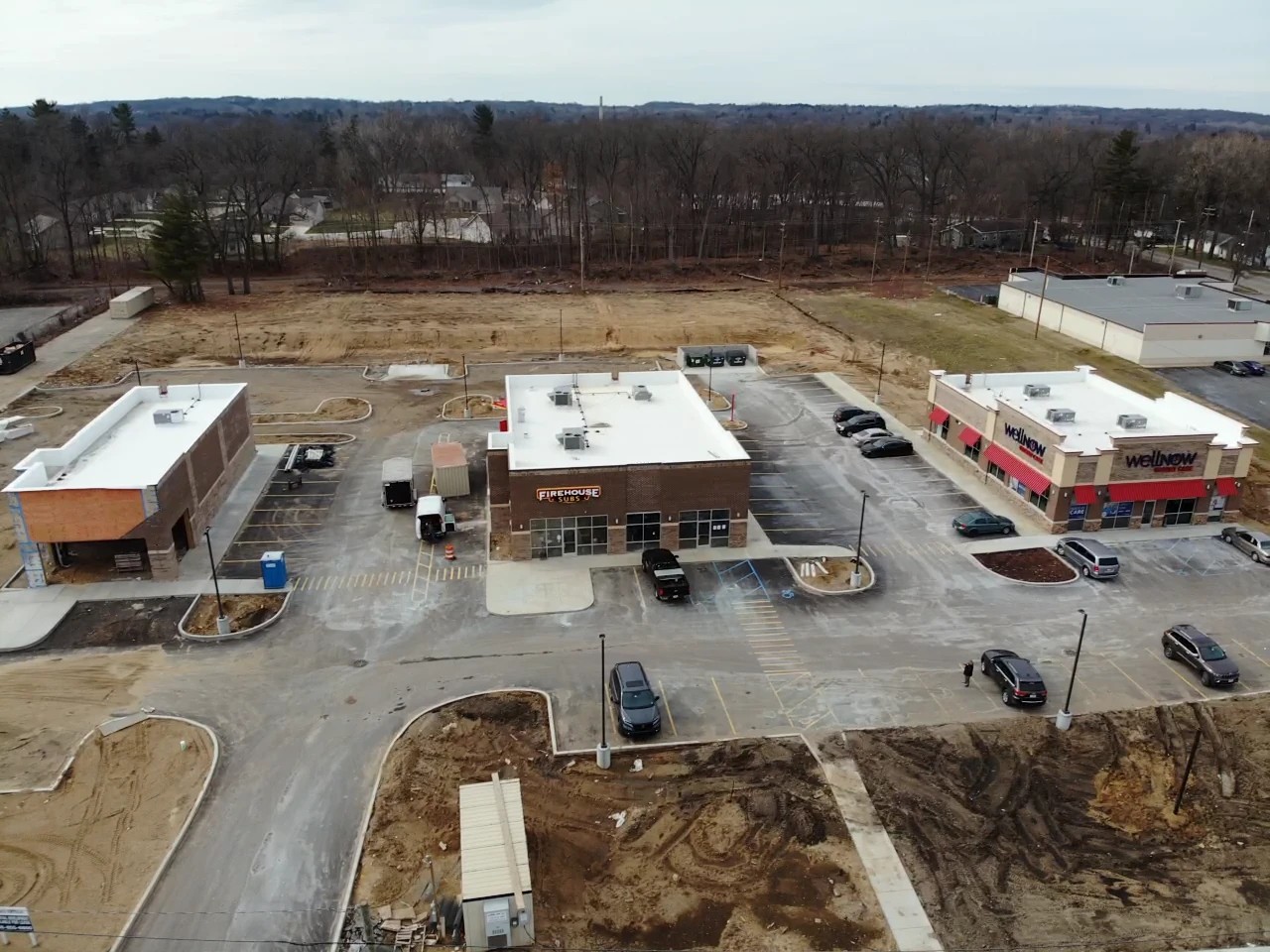 Osceola, IN 2 An aerial view highlights a newly developed commercial strip featuring multiple brick buildings with clean, flat white roof systems, demonstrating a prime example of professional commercial roofing services.