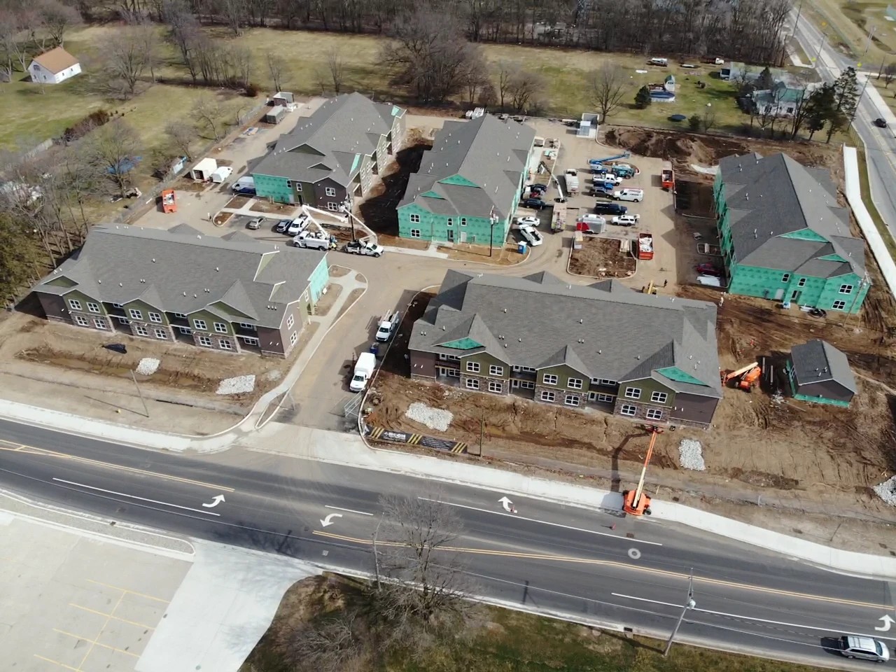 Bristol, IN 2 An aerial perspective reveals a multi-family commercial housing complex under active construction with work vehicles on-site and several large buildings featuring freshly completed shingle roofs, highlighting a major project completed with expert commercial roofing services.