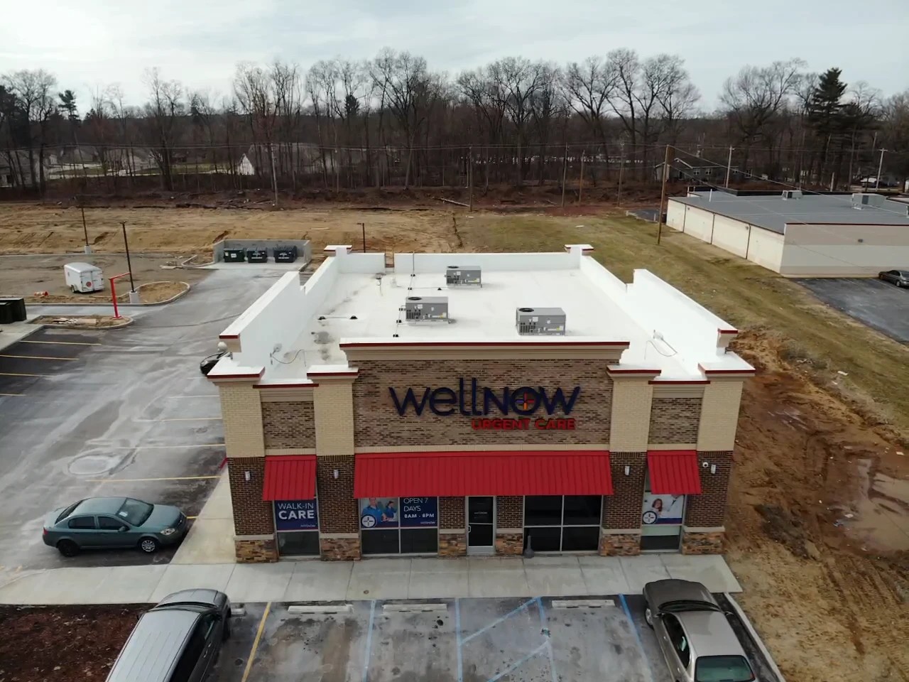 Granger, IN 2 An aerial view captures a WellNow Urgent Care building with a clean, flat white rooftop, demonstrating the scale of professional commercial roofing services.