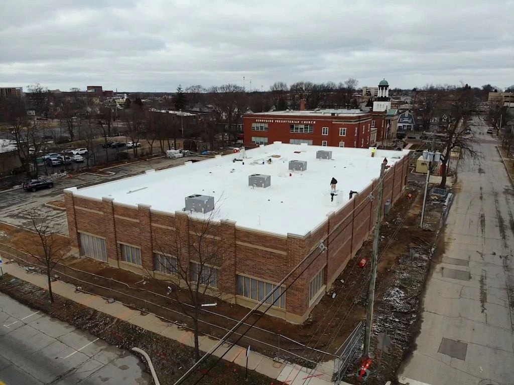 Winamac, IN 2 An aerial view highlights the newly completed white flat roof on a large brick building, showcasing high-quality commercial roofing services.