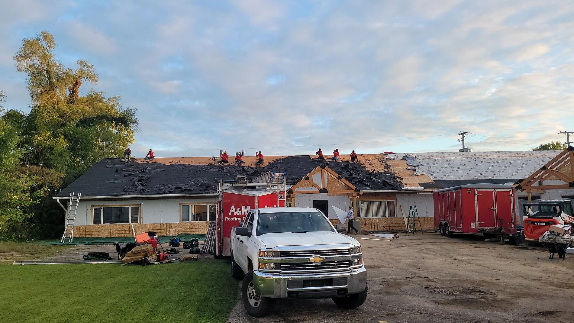 Work trucks and crew members positioned around a building mid-renovation showcase the scope of professional exterior services.
