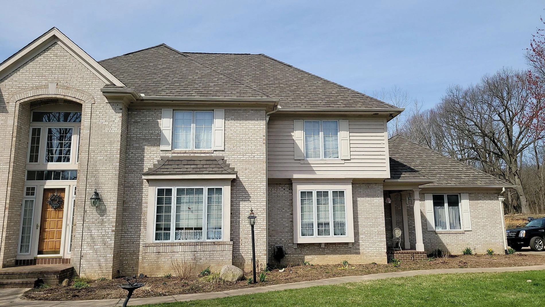 A large two-story brick-and-siding home features pristine roofing, windows, and masonry, showcasing comprehensive exterior services.