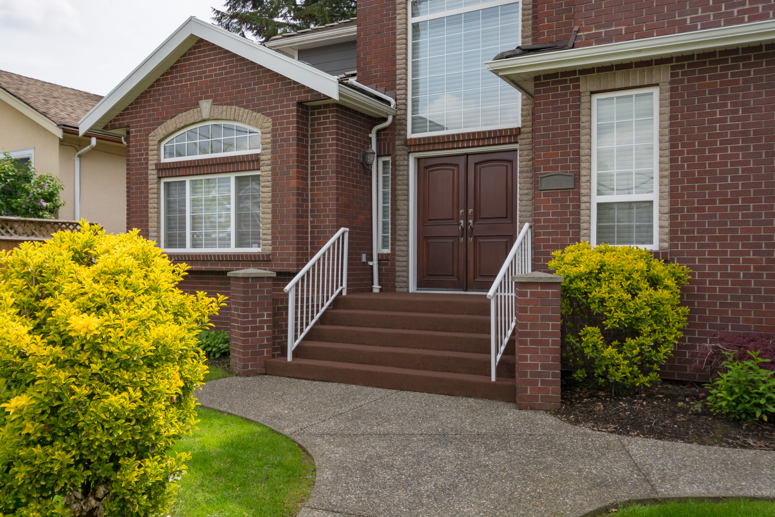 Elkhart, IN 3 A double wooden entryway framed by brick architecture showcases how replacement doors enhance curb appeal alongside expert roofing services.
