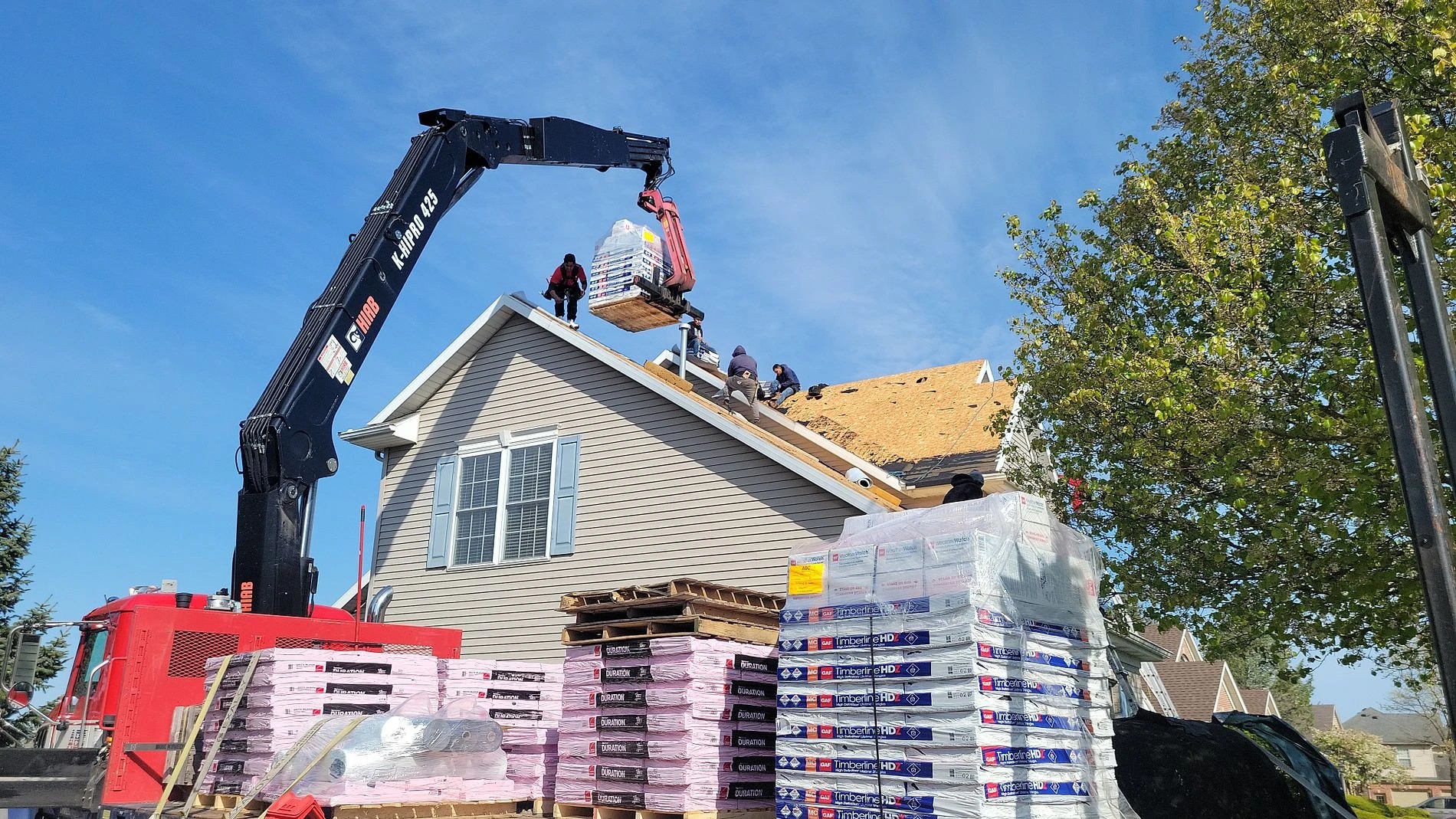 Goshen, IN 3 A crane delivers roofing materials to a home's roof as contractors prepare to perform professional roofing services.