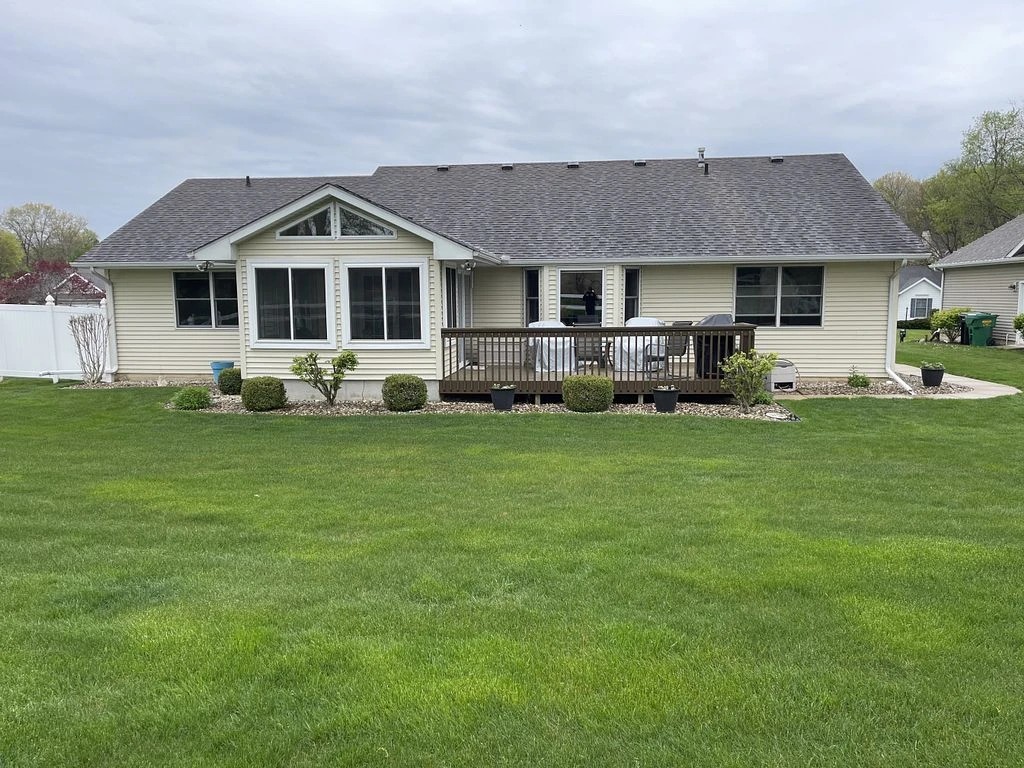 Benton Harbor, MI 3 The back of a single-story home features a well-maintained shingle roof, beige siding, and a wooden deck, showcasing comprehensive exterior services.