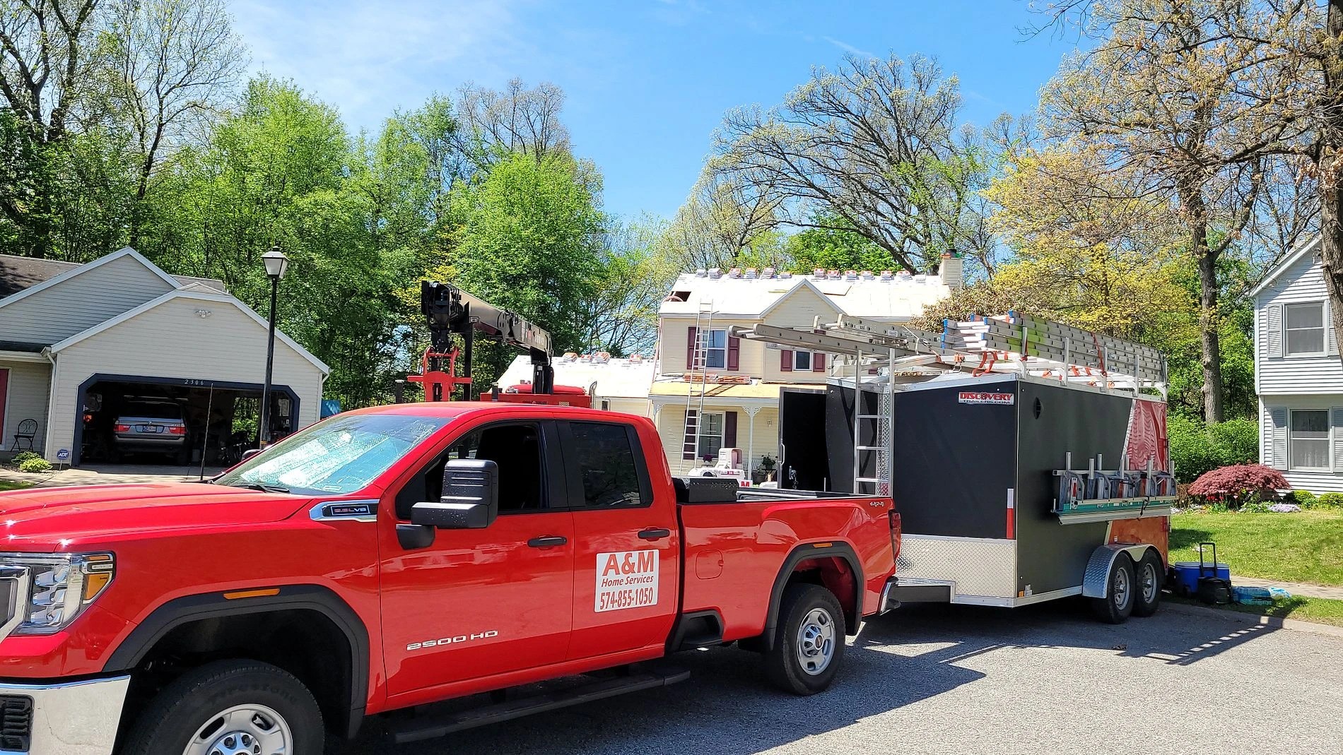 Saint Joseph, MI 3 A red work truck and equipment trailer parked outside a residential home illustrate professional exterior services in action.