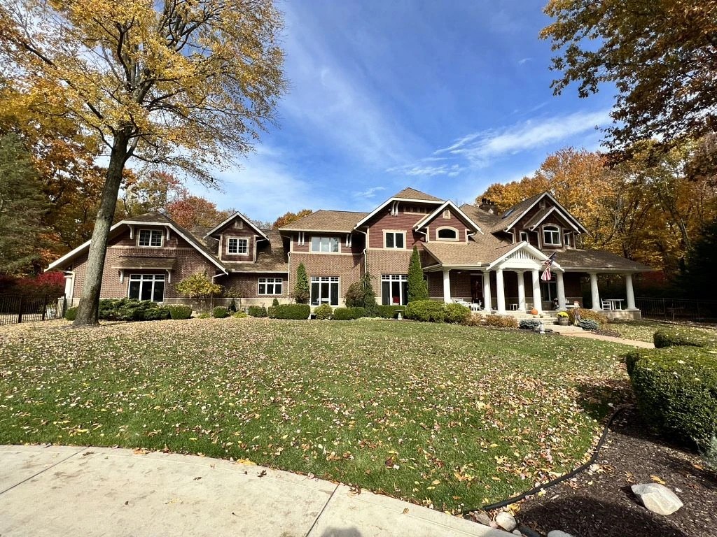 Lapaz, IN 3 A spacious brick estate is framed by vibrant autumn trees, showcasing a multi-gabled roof and detailed trim completed with expert exterior services.