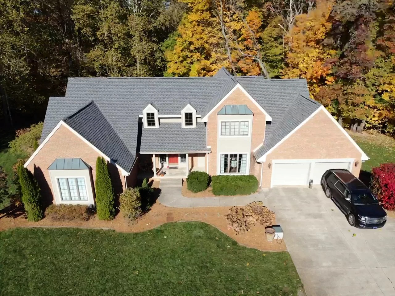 Donaldson, IN 3 An aerial view captures a large two-story brick home with dormer windows and a grey shingled roof maintained through comprehensive exterior services.